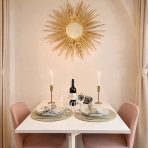 Une table à manger avec deux chaises, une bouteille de vin, des verres et des bougies.