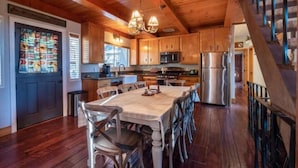 Interior de madera con cocina, comedor y escalera.