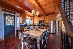 Interior de madera con cocina, comedor y escalera.