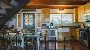 Una cocina rústica con armarios de madera, un comedor con sillas de madera y una escalera.