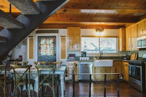 Una cocina rústica con armarios de madera, un comedor con sillas de madera y una escalera.