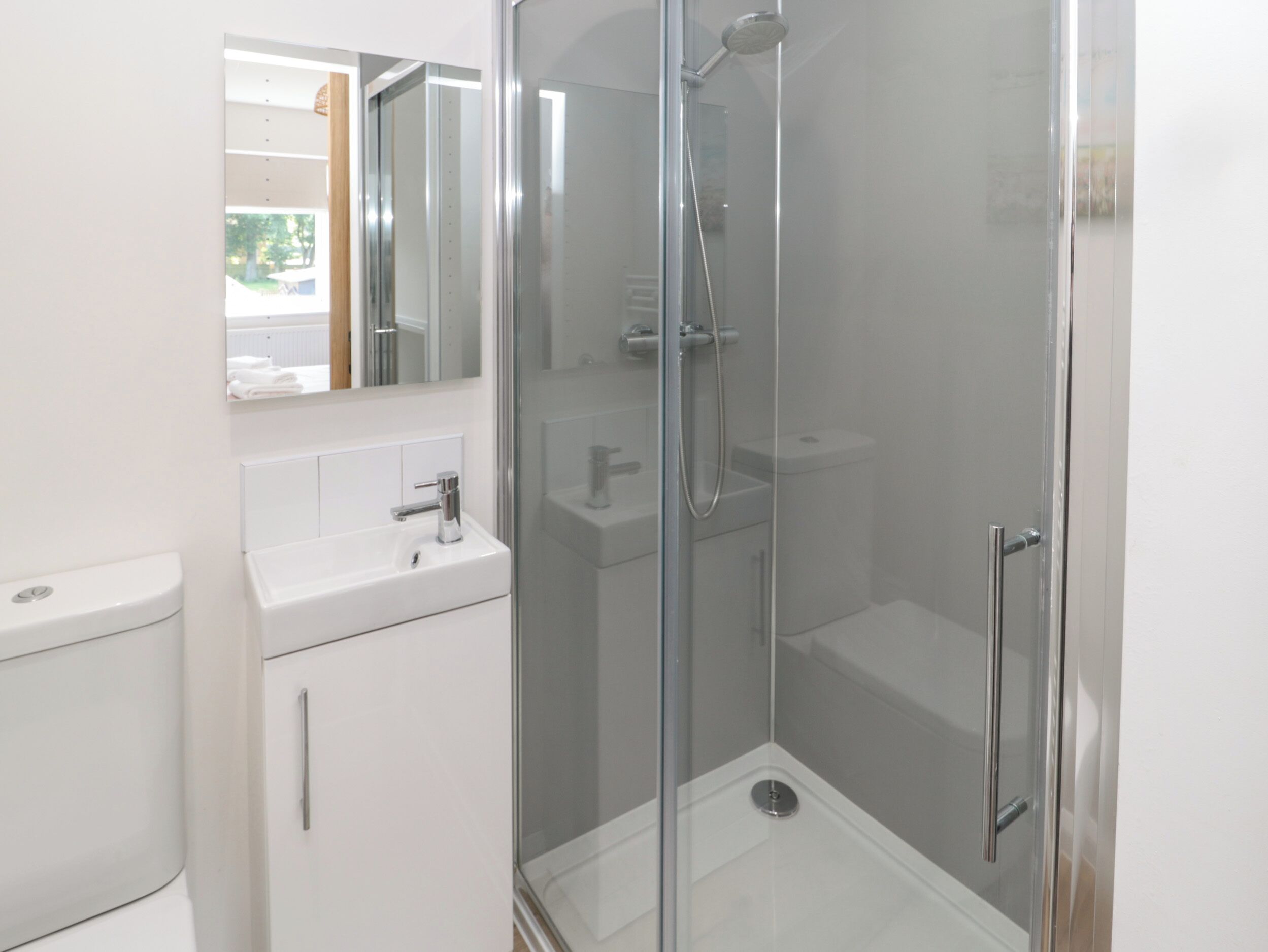 A modern bathroom with a glass-enclosed shower, a white sink, and a mirror above the sink.