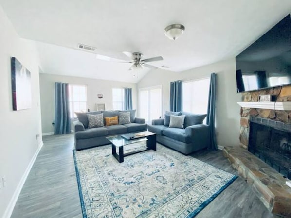 A spacious living room with a fireplace, two sofas, a coffee table, and a large rug.
