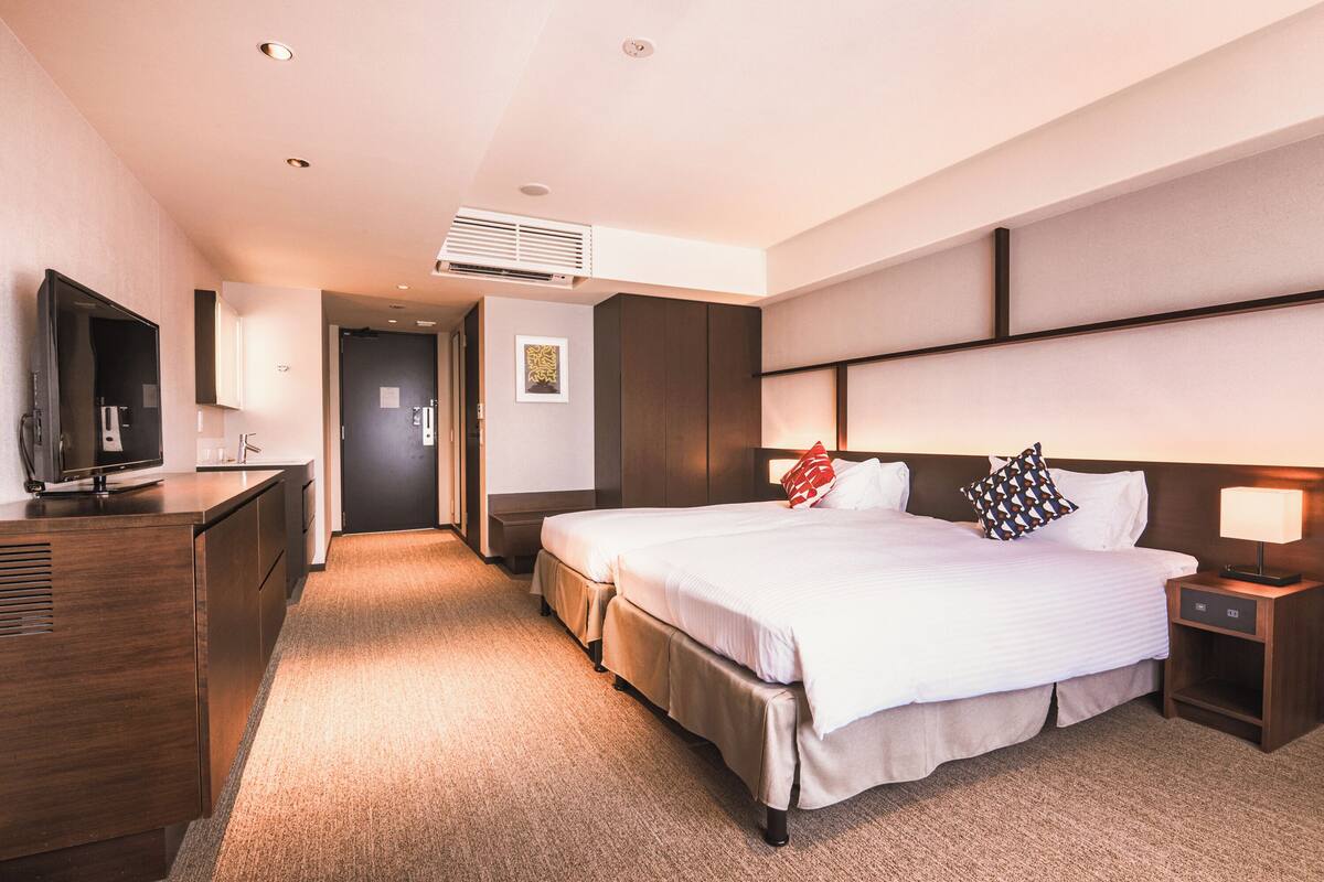 A hotel room with a large bed, a TV, a desk, and a wardrobe.