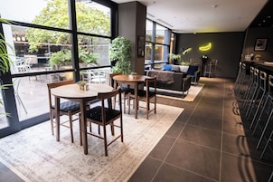 A modern interior with large windows, wooden furniture, and potted plants.