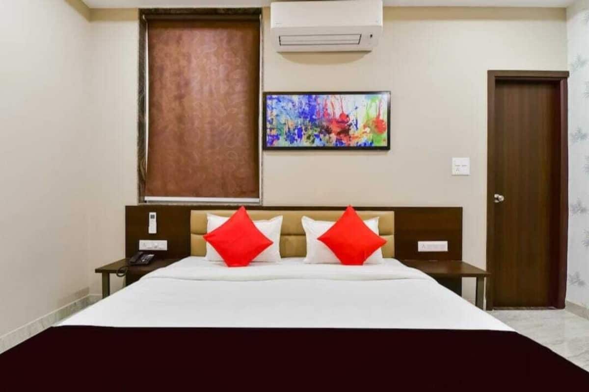 Ein Hotelzimmer mit Bett, Nachttisch, Telefon, einem Gemälde und einer Klimaanlage.