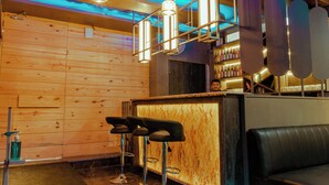 A bar area with wooden panel walls, hanging pendant lights, and bar stools. - HOTEL JAI HARSH BY DIVYANSHI HOSPITALITY (Jaipur)