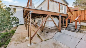 Una casa en construcción con terraza de madera y escaleras que suben a un segundo piso.