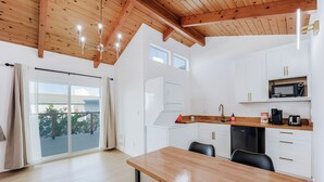 Una cocina moderna con armarios blancos, una mesa de comedor de madera y un microondas empotrado.