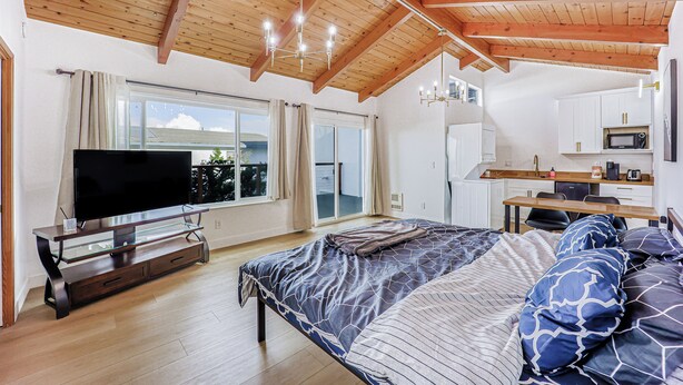Un dormitorio con una cama grande, televisión y una kitchenette.
