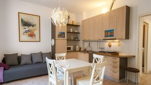 A modern kitchen with white cabinetry, a dining area with white chairs, and a gray sofa. - Chinatown-Sarpi 1860 Apt w/Elevator. Walk to Duomo & Brera. Easy to San Siro (Milano)