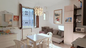 A compact kitchen with a dining area, a sofa, and a window with metal bars. - Chinatown-Sarpi 1860 Apt w/Elevator. Walk to Duomo & Brera. Easy to San Siro (Milano)