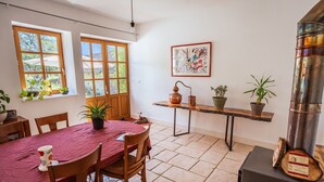 A dining area with a red tablecloth, wooden chairs, a coffee table, and a potted plant. - Maison Entière Haut Valromey (HAUT-VALROMEY)