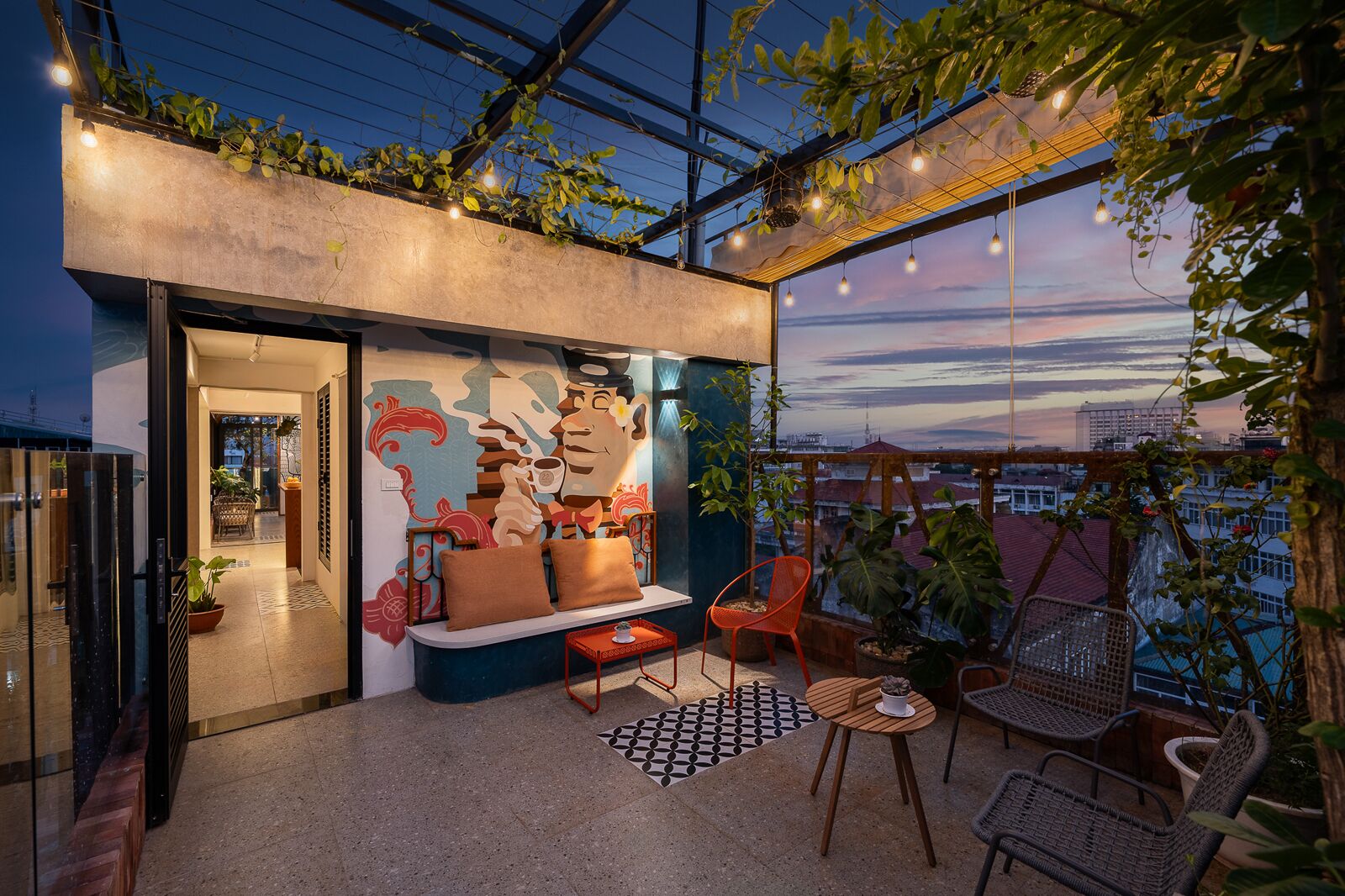Un espacio moderno para vivir con sofá, sillas y vista a la ciudad al anochecer.