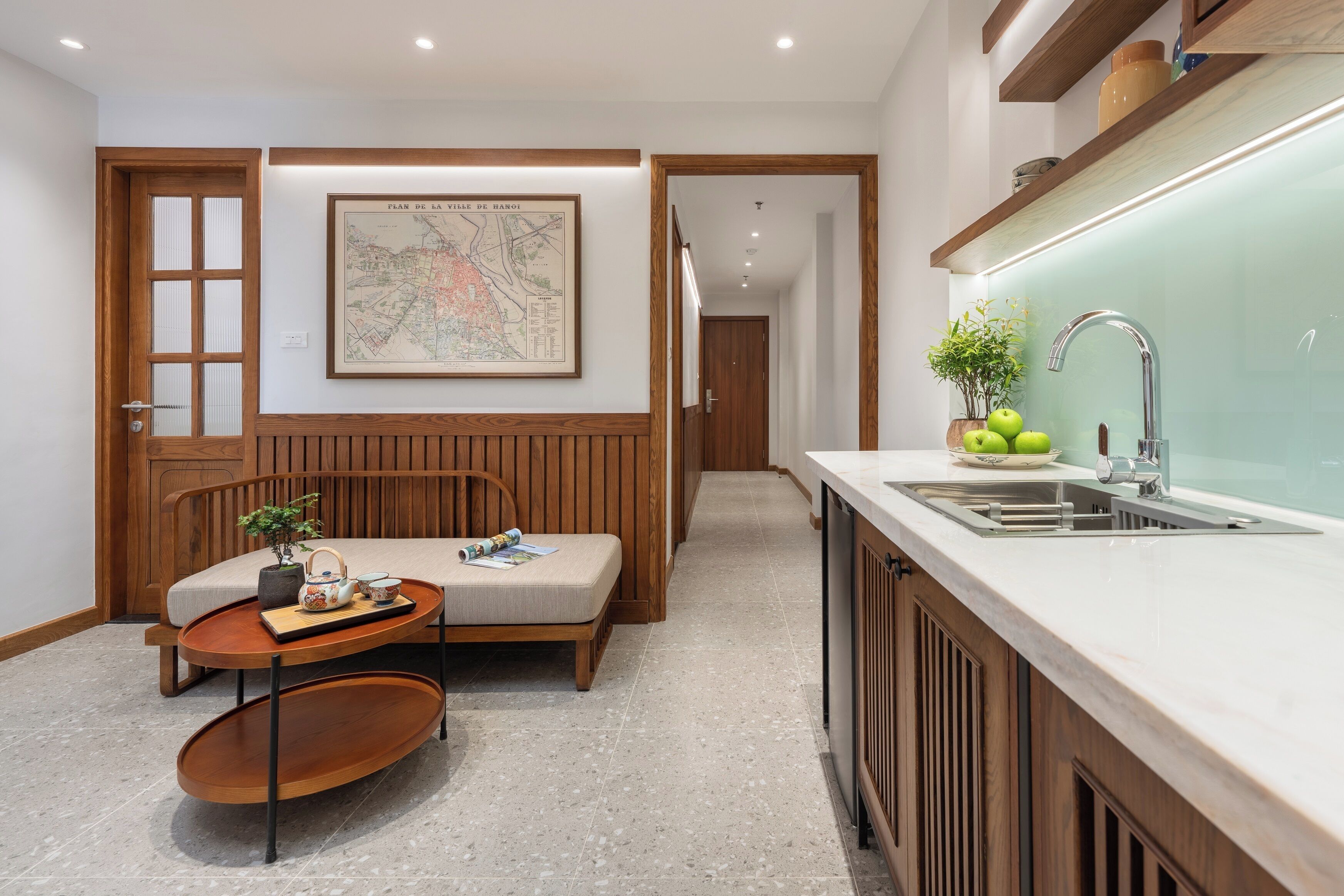 A modern kitchen with a wooden bench, a map on the wall, and a sink with a green plant.