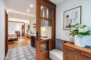 A compact hotel room with a wooden cabinet, a small sink, a bed, and a dining area. - Le Parfum Apartment And Hotel (Hanoi)