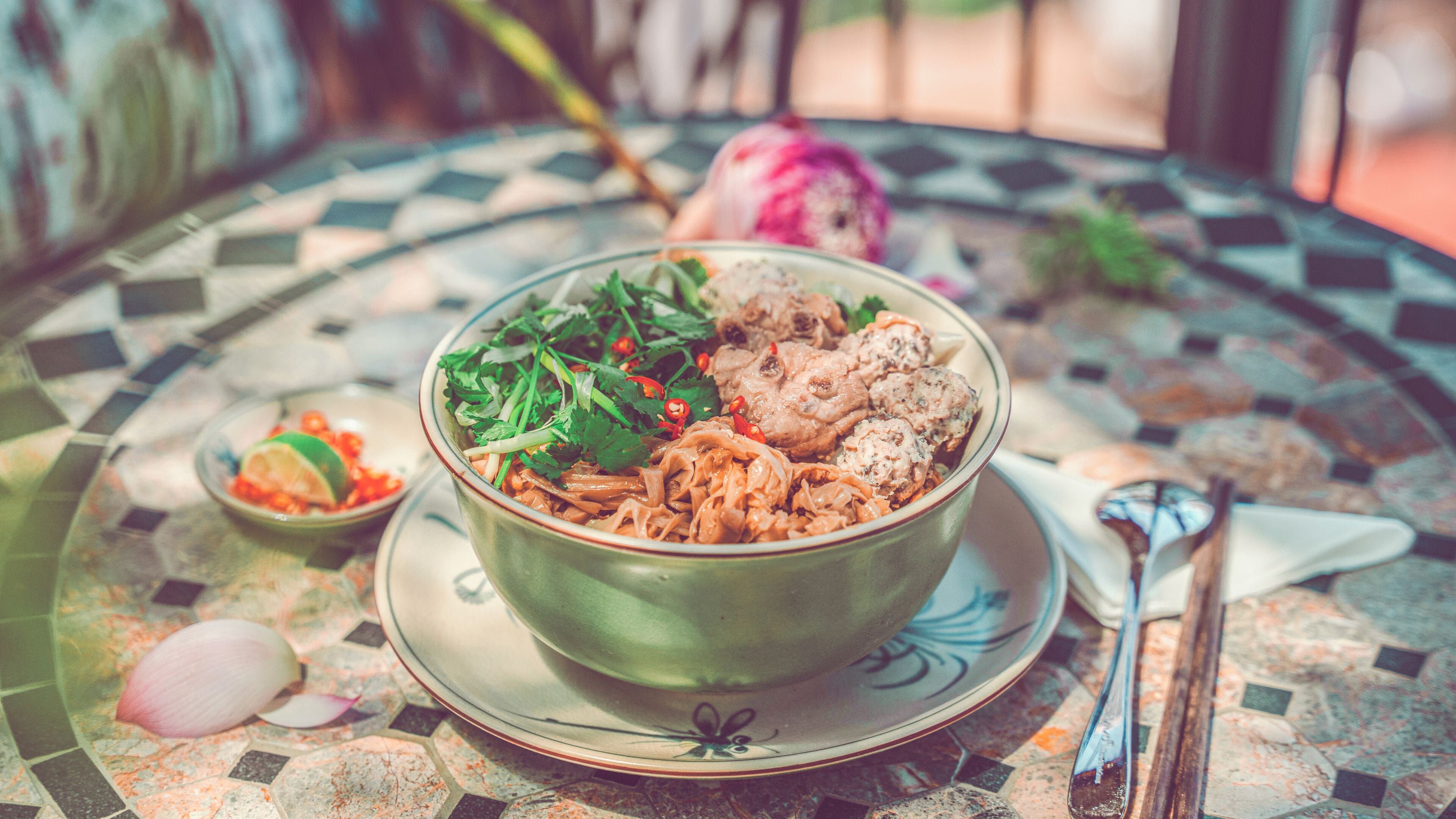 A bowl of food on a table with a patterned tablecloth.