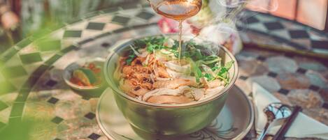 A bowl of soup with steam rising, placed on a patterned table.