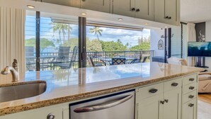 A kitchen with a large island, a built-in dishwasher, and a view of the outdoors.