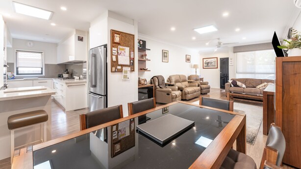 A modern kitchen with a refrigerator, a dining table with chairs, a sofa, and a coffee table in a living area. - Highett Charm - 3 bedroom Unit (Highett)