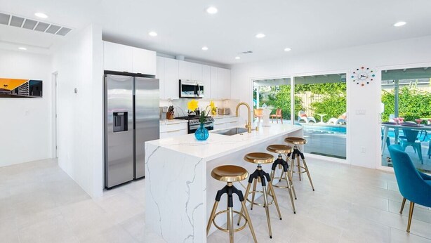 Cocina moderna con una isla central, electrodomésticos de acero inoxidable y vistas a un área de piscina exterior.