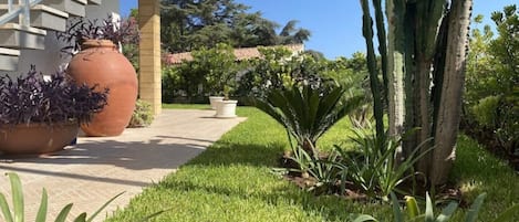 A pathway leading to a building with a staircase and large terracotta pots.