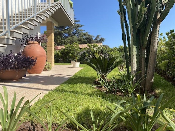 A pathway leading to a building with a staircase and large terracotta pots.