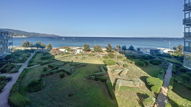 Un jardin aménagé avec des allées, une vue sur la mer et un panorama sur la ville au loin.