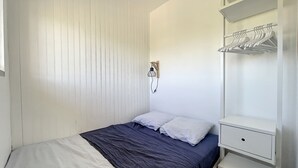 Une chambre à coucher comprenant un lit, une table de chevet, une armoire et un luminaire fixé au mur.