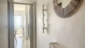 Un couloir avec un mur blanc, un miroir rond et un banc blanc.