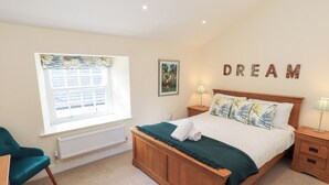 A bedroom with a wooden bed, a window with a view, a chair, and a wall with the word "DREAM" spelled out in letters. - 4 Martindales Yard (Kendal)