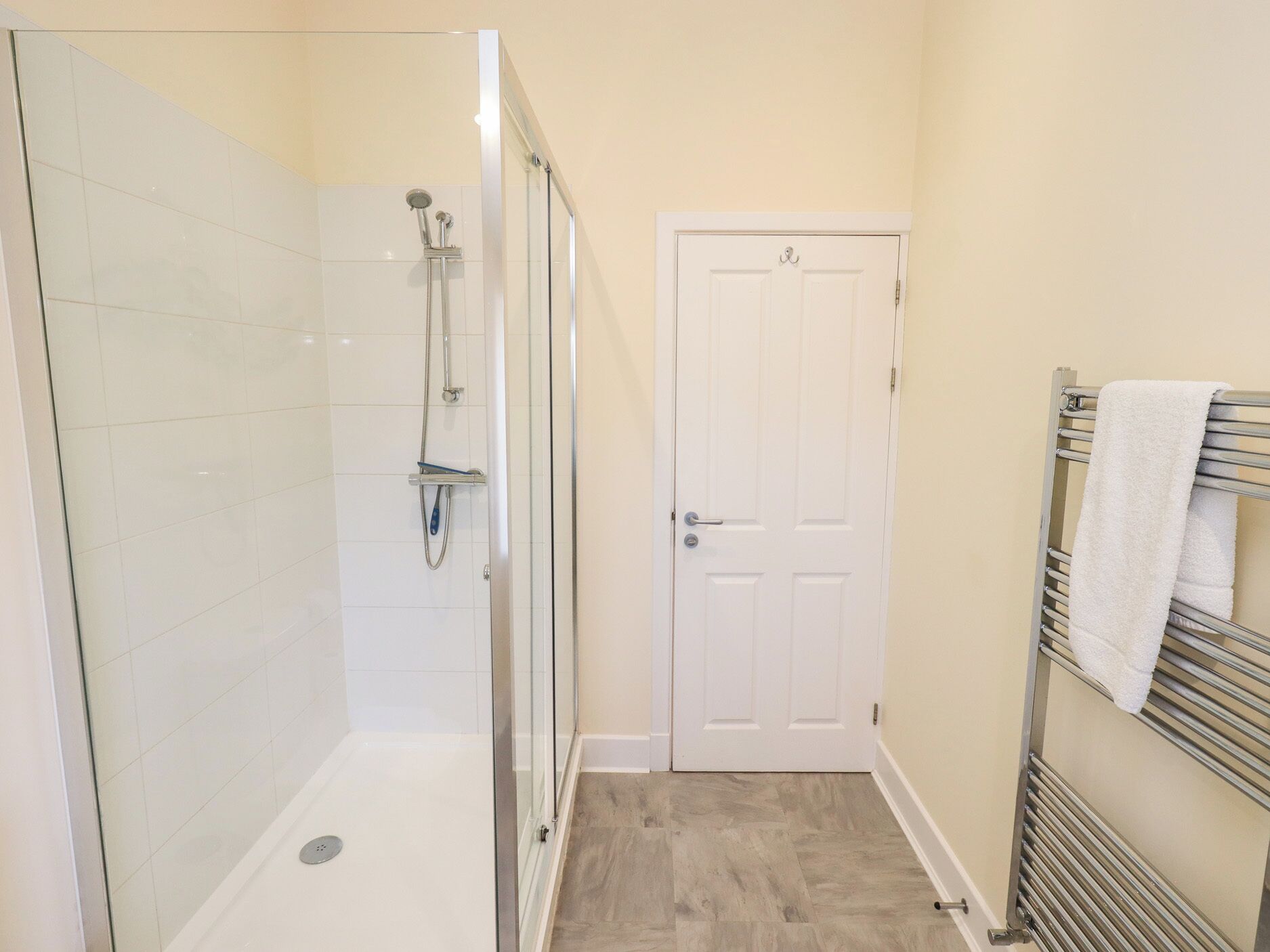 Une salle de bain avec une douche à parois de verre, une porte blanche et un porte-serviettes avec des serviettes.