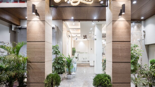 Entrada de hotel con un letrero de neón que dice "Megdoot", plantas en macetas y un interior moderno con una recepción.