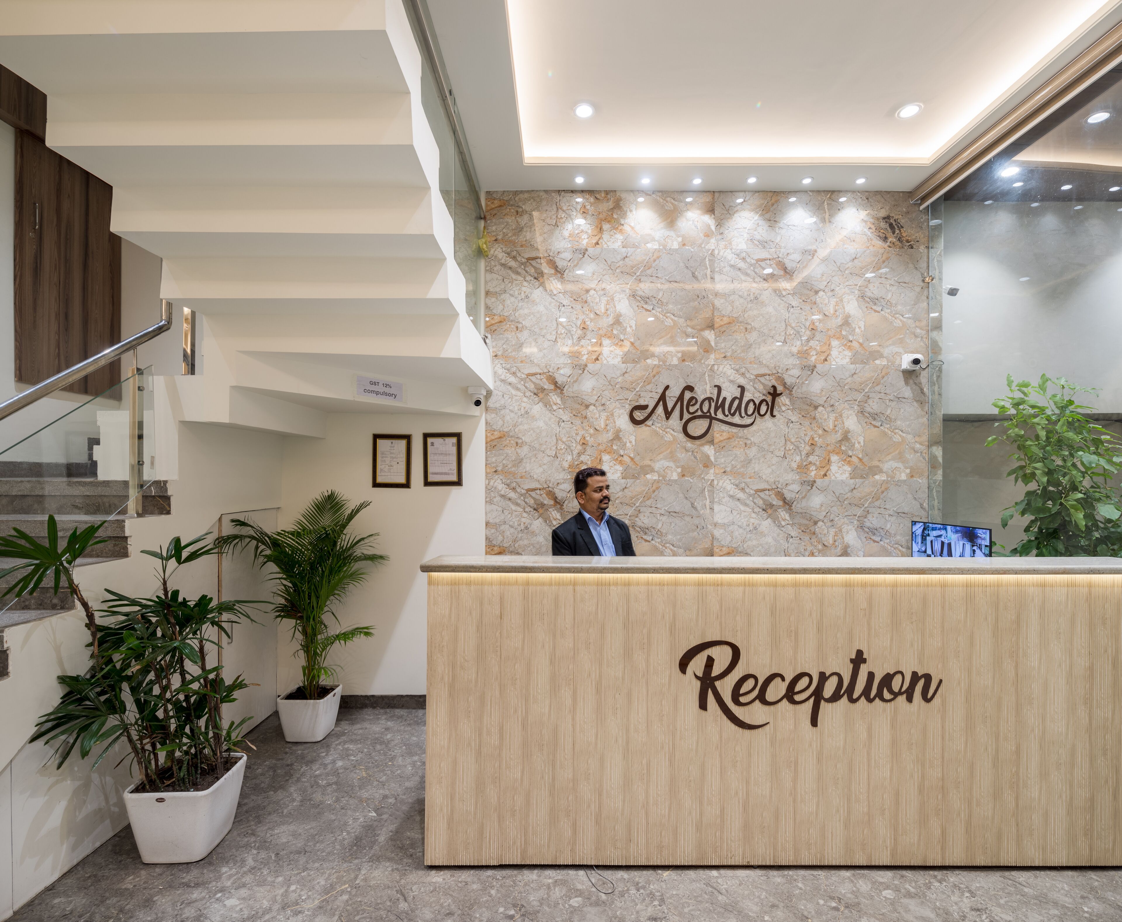 A reception desk with a marble wall and the name "Megdoot" above it.