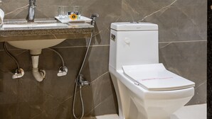 Un baño con pared de mármol, un lavamanos con espejo y un inodoro.
