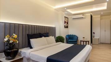A modern bedroom with a large bed, bedside tables, a chair, and an air conditioning unit.