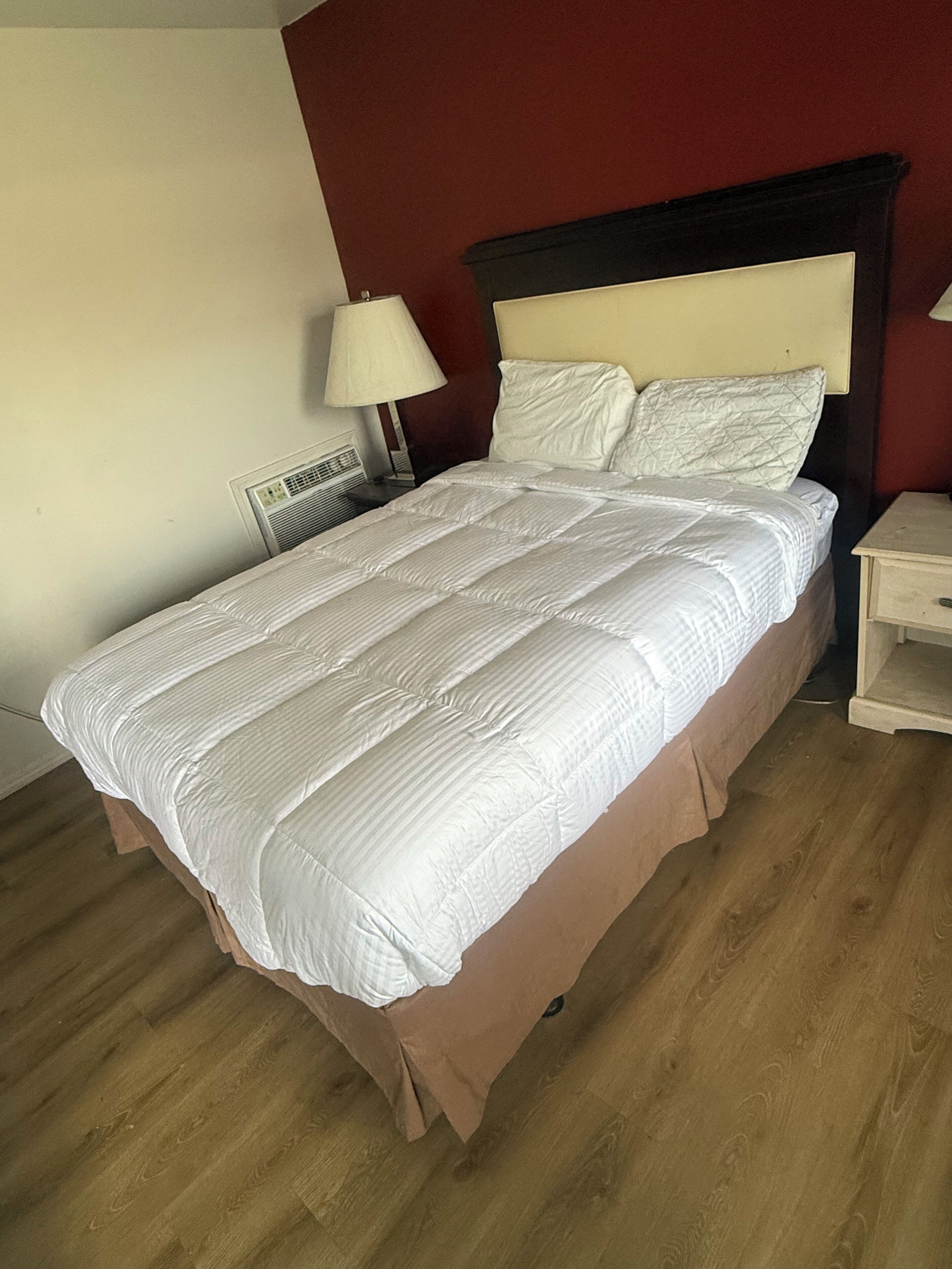 Un lit avec une tête de lit, une lampe de chevet et une table de chevet.