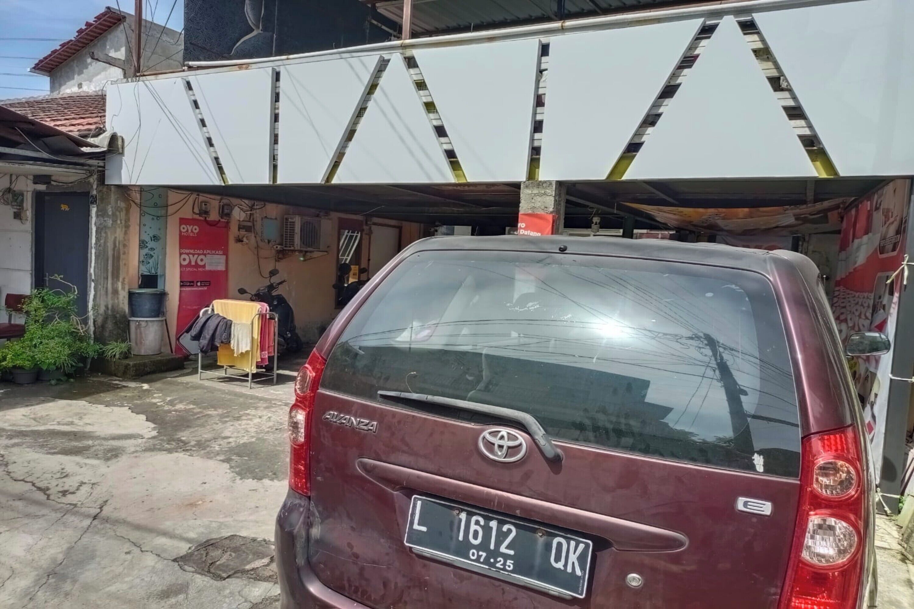 Un coche color burdeos aparcado frente a un edificio con un cartel que dice "OYO".