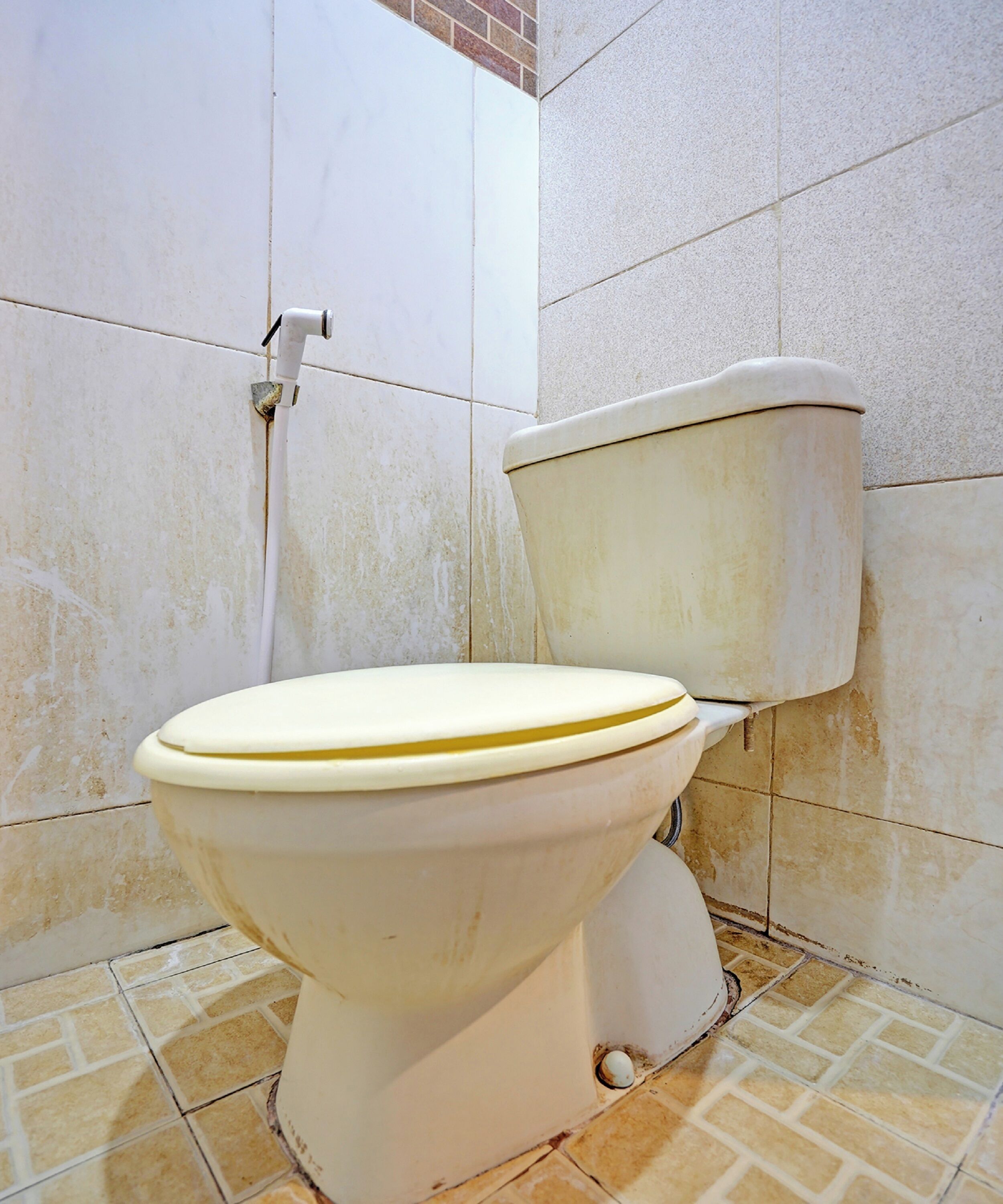 Toilet in een badkamer met betegelde wanden en vloer.