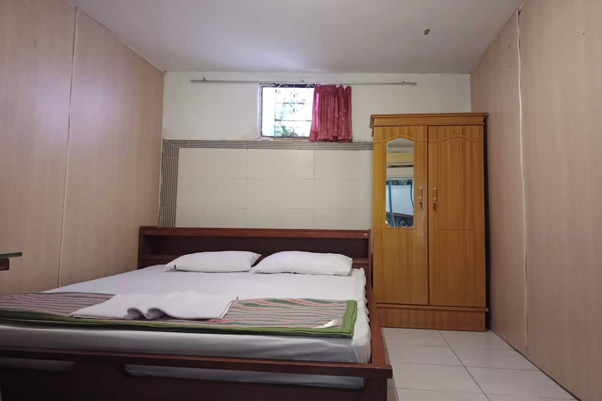 Ein Schlafzimmer mit einem hölzernen Bett, einem Kleiderschrank und einem Fenster mit Vorhang.