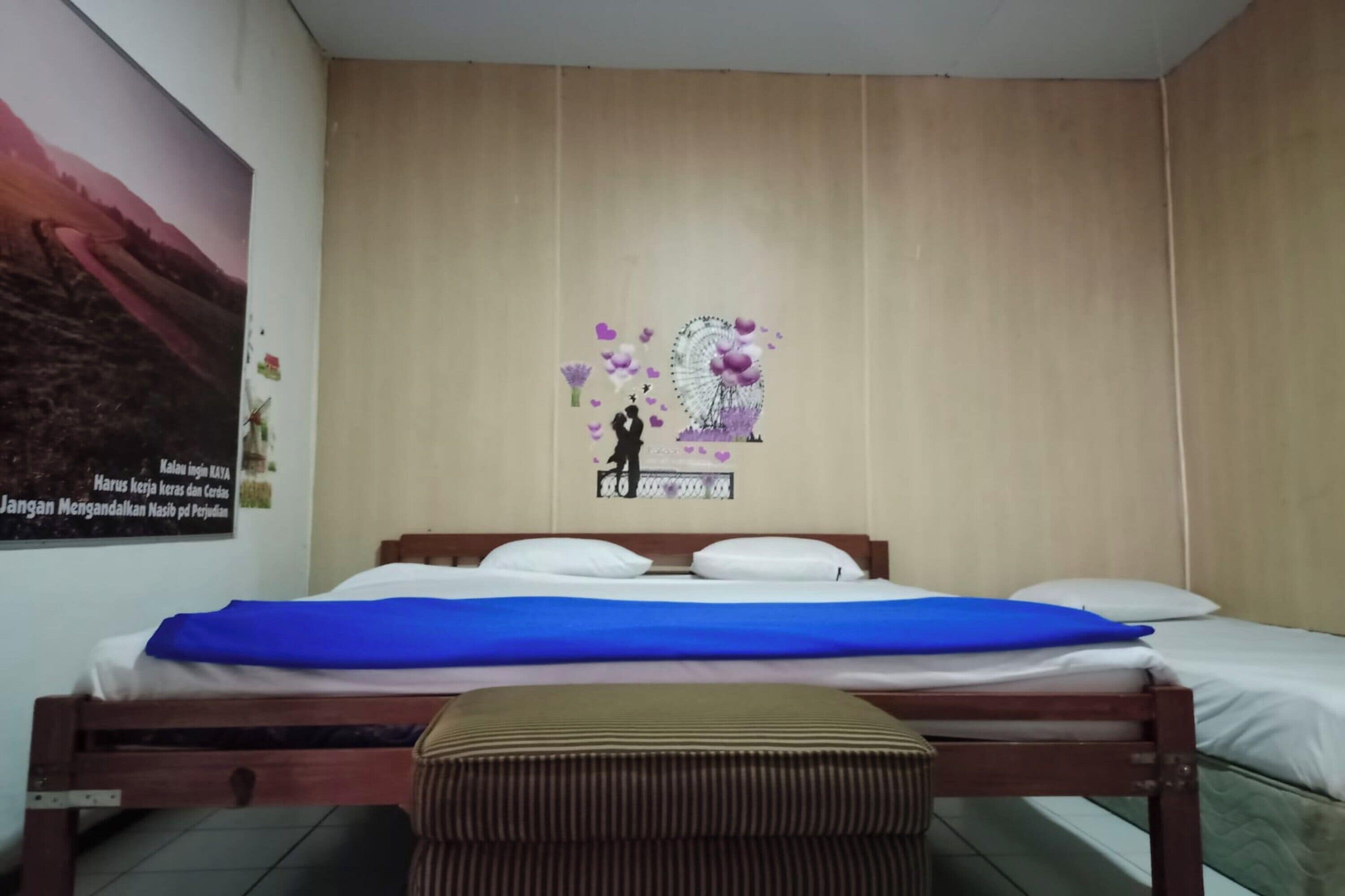 A bedroom with a wooden bed, a blue bedspread, and a wall poster.
