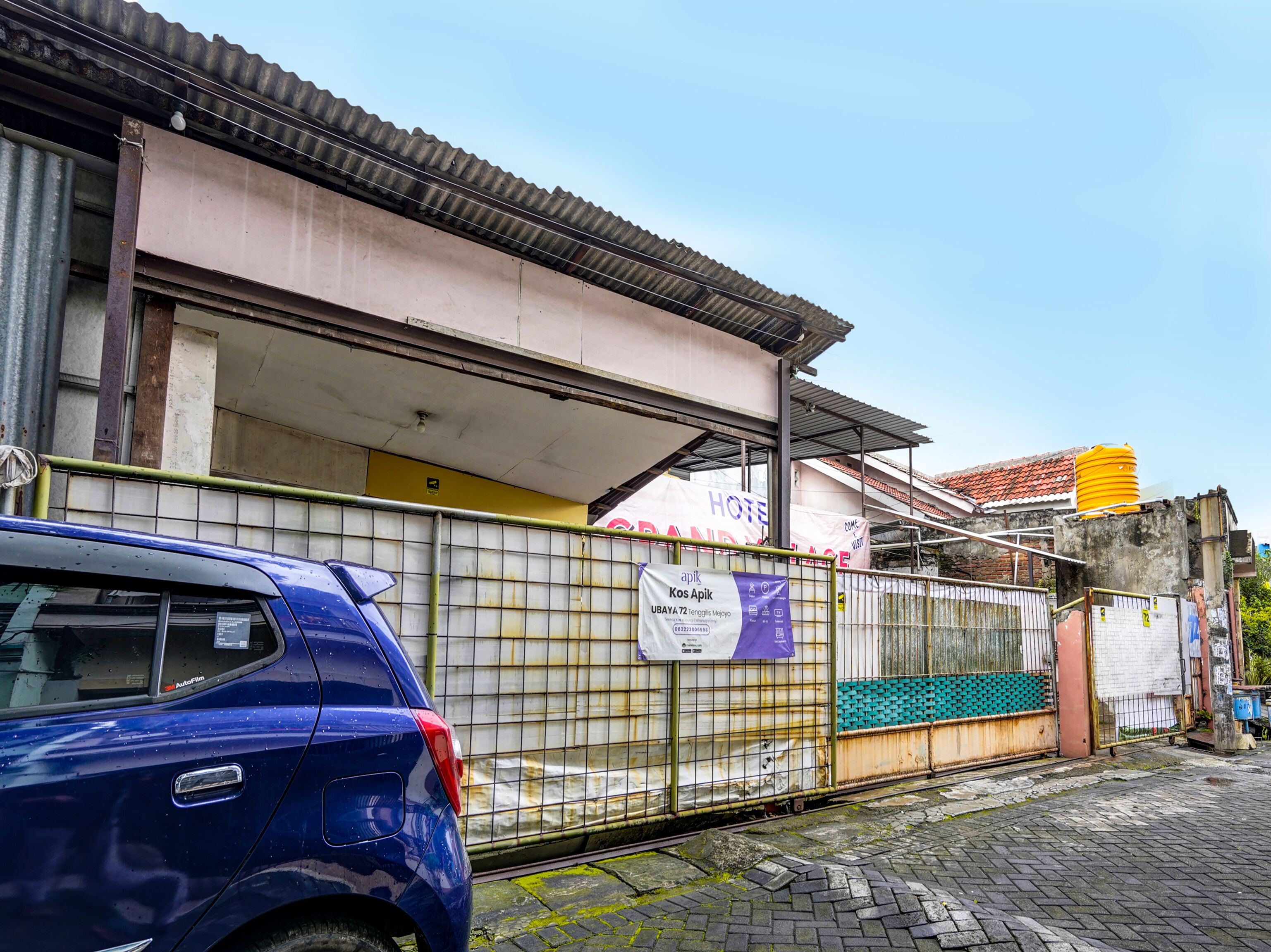 A building with a corrugated metal roof, a gated entrance, and a sign advertising a hotel.