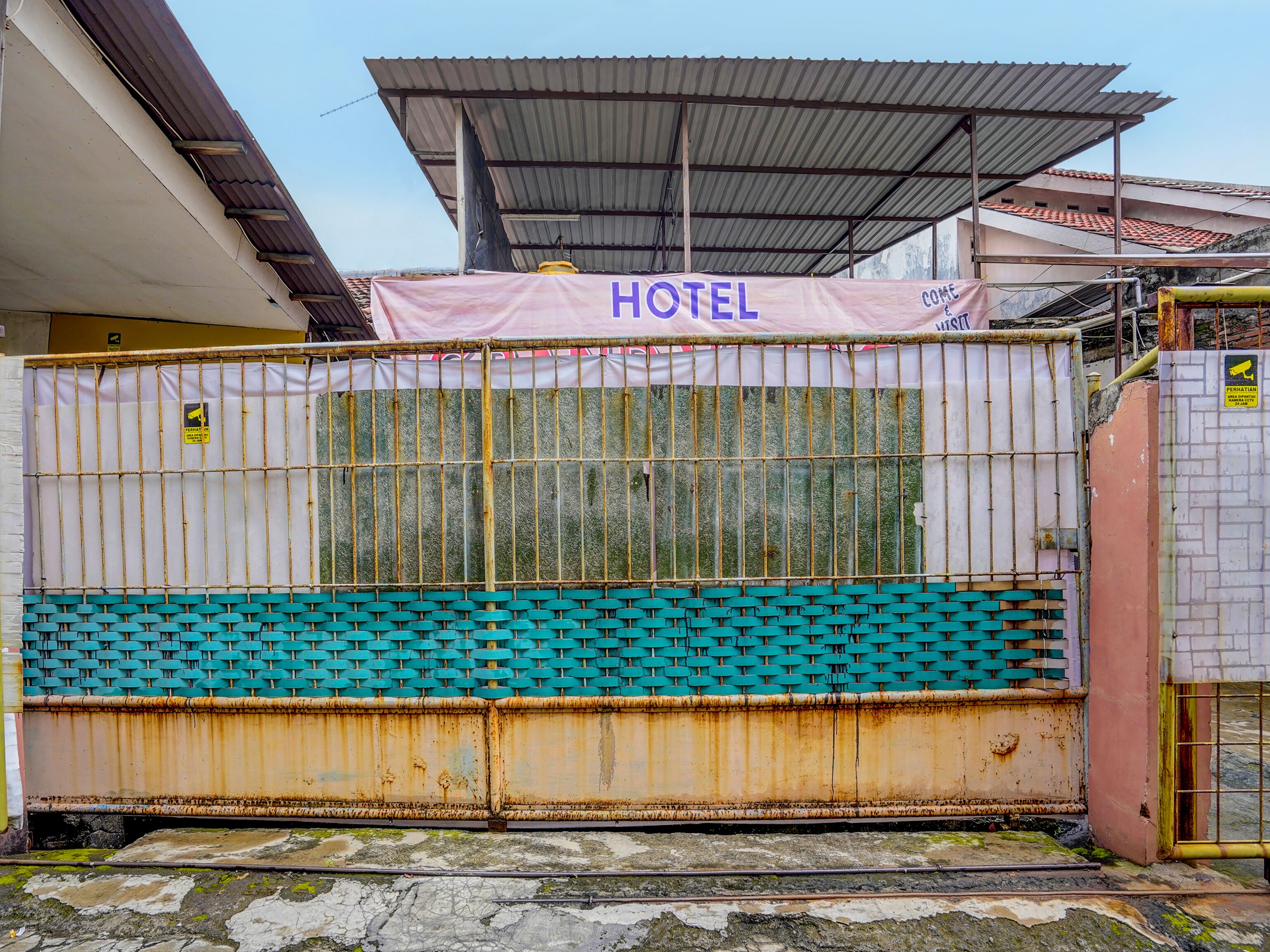 A hotel with a metal gate, a sign reading "HOTEL", and a tiled roof.