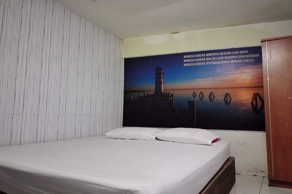 Ein Hotelzimmer mit einem Bett, weißen Wänden und einem großen Poster mit einem Leuchtturm an der Wand.