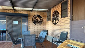Un patio couvert avec des sièges d’extérieur, une terrasse en bois et des éléments décoratifs sur les murs.