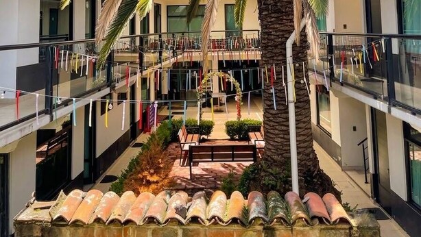 A modern building with a central courtyard, a palm tree, and balconies with clotheslines. - La Palma Co-living (Tecamac)