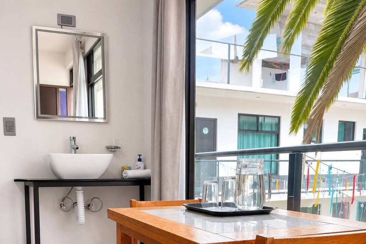 A modern kitchen with a white sink, a black countertop, and a wooden dining table with chairs.