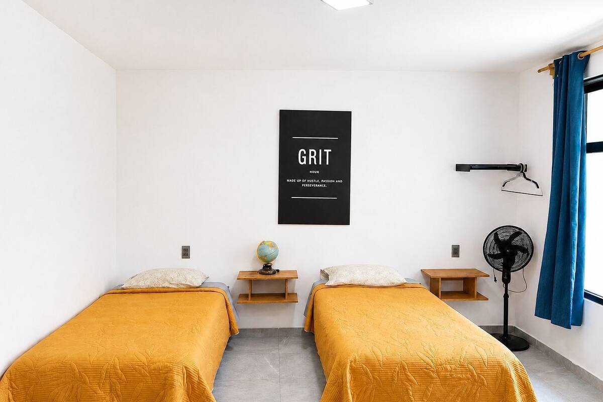 A room with two beds, a globe, a desk, a fan, and a motivational poster.