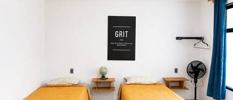 A room with two beds, a globe, a desk, a fan, and a motivational poster.