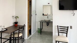 A room with a dining table, chairs, a TV mounted on the wall, a sink, and a mirror. - La Palma Co-living (Tecamac)